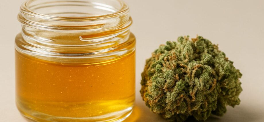 A jar of cannabis extract next to a bud of cannabis flower on a neutral background.